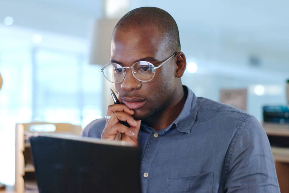 Business owner and high-income earner studying tax documents on a laptop, debating whether to hire a tax strategist.